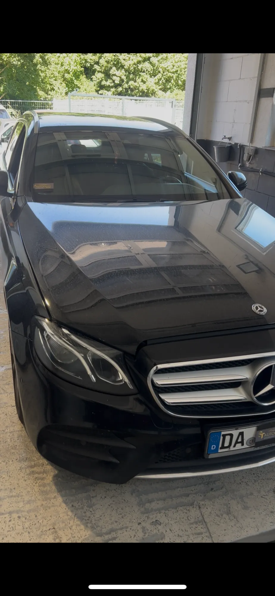 Schwarzer Mercedes-Benz mit neuer Windschutzscheibe im Werkstattbereich